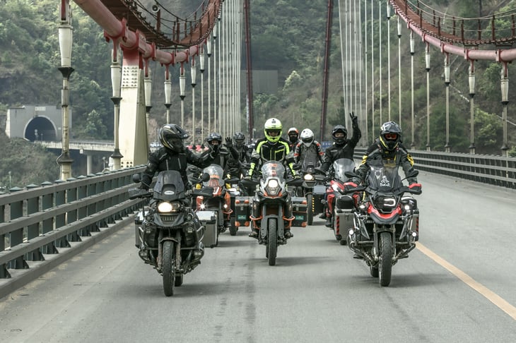 Group of BMW motorcyclists crossing a bridge.