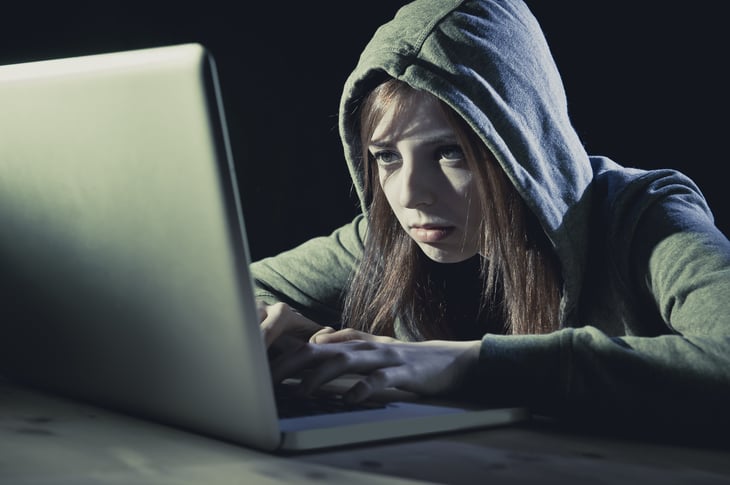 Hooded woman looking at computer screen