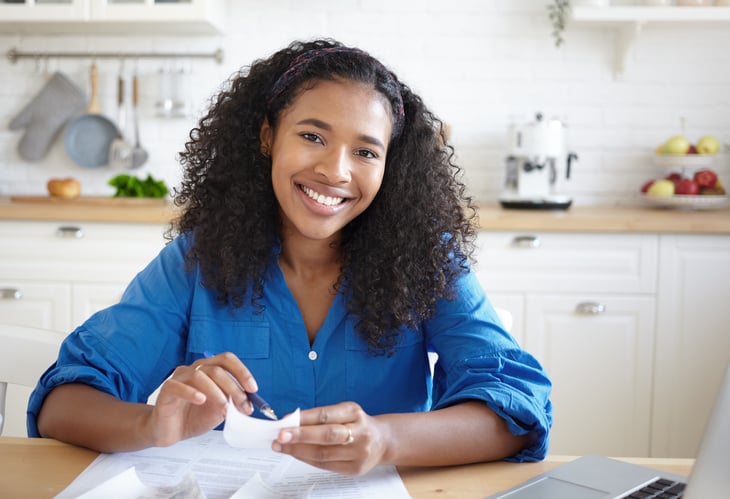 a young black woman makes a budget at her kitchen table