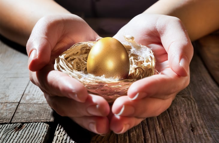 Woman clasps a golden nest egg in her hands