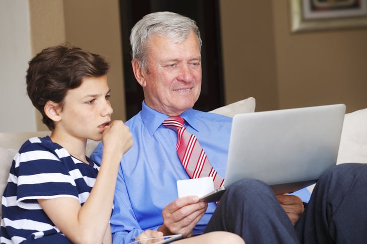 Man teaching his grandchild how to use a credit card