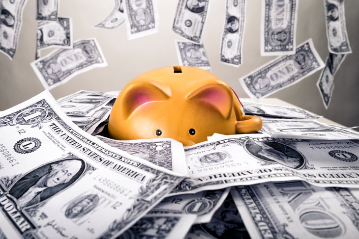 Money piles up around a piggy bank