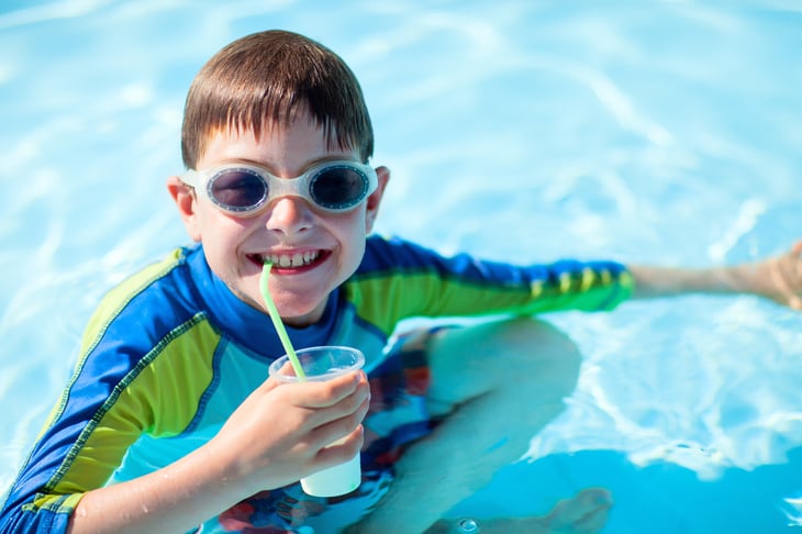 A boy sips a drink at a resort pool