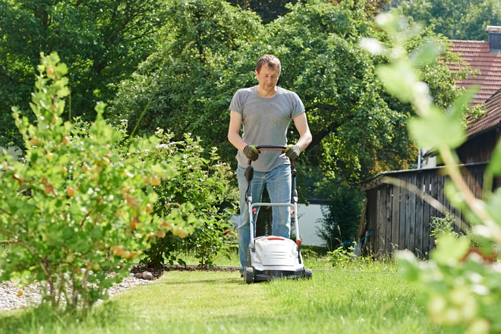 A man the cuts grass with a lawnmower