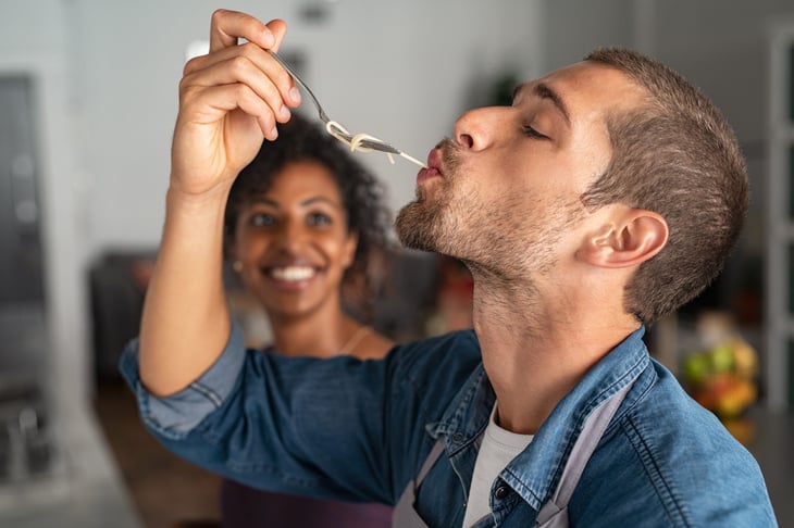 A man savors a bite of his meal while a woman smiles next to him