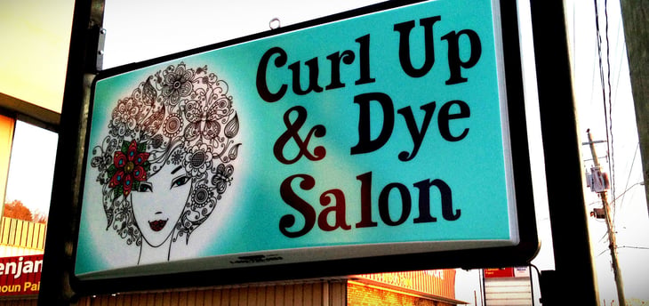 Shop front with sign that says Curl Up and Dye