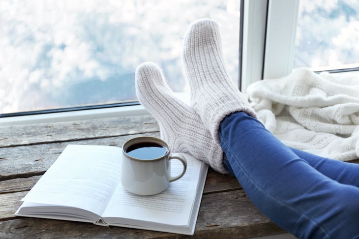 A person relaxes inside with snow outside