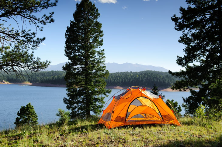 Orange camping tent next to a lake