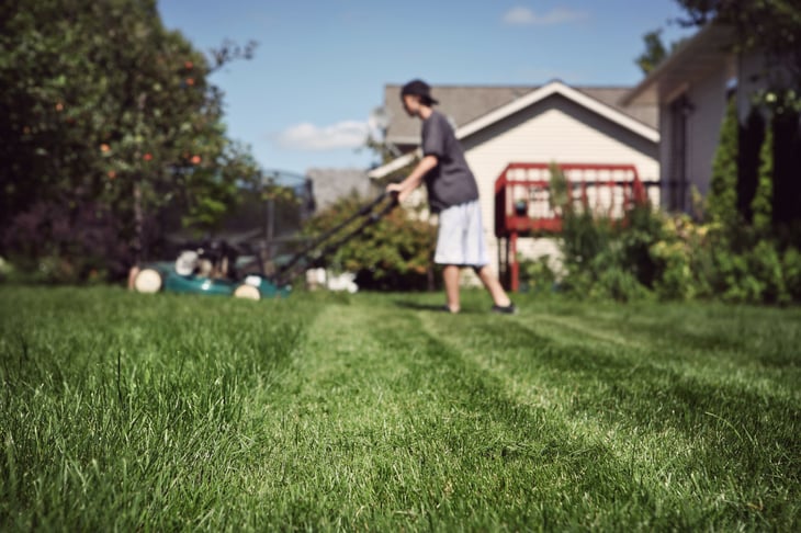 Teenage boy mowing lawn.
