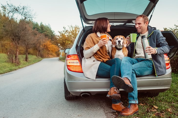 A couple on a road trip stop drinking from a thermos