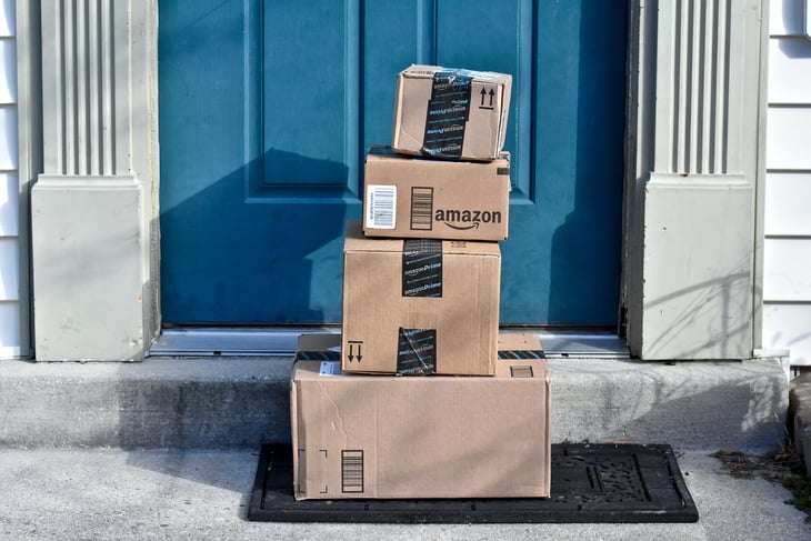 Packages from Amazon are piled in front of a door