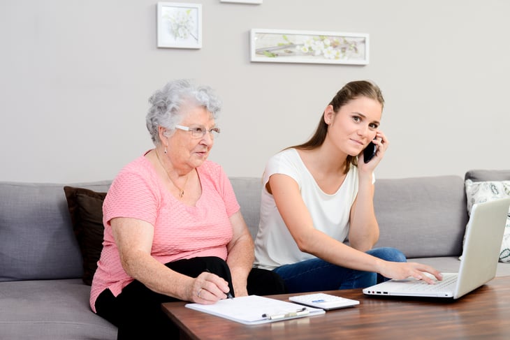 Young woman on phone sitting with older woman.