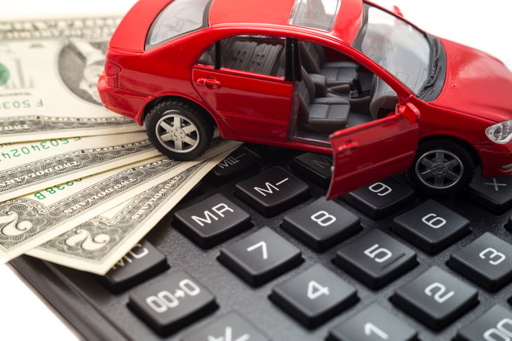 A model car sits on top of a pile of money and a keyboard