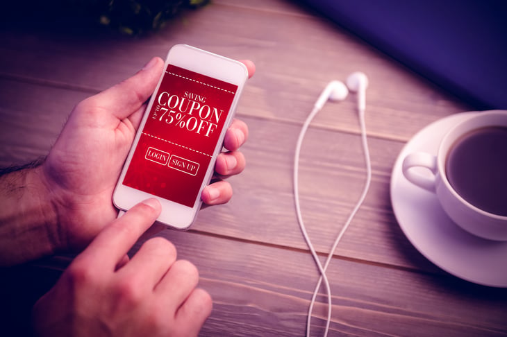 Hands holding a cellphone with a digital coupon showing.