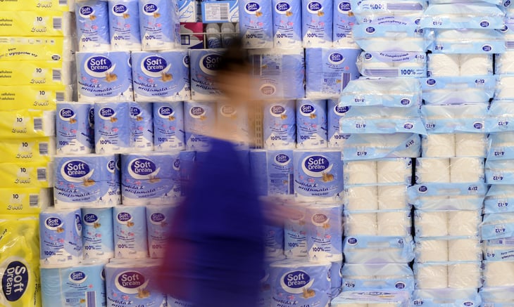 Person walking past stacks of toilet paper.