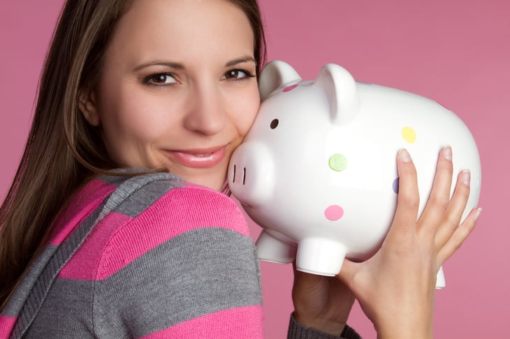 A woman hugs a piggy bank