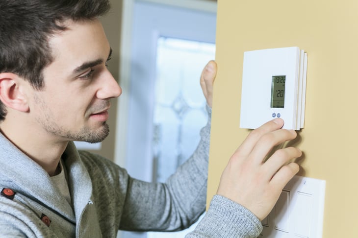 Man adjusting thermostate