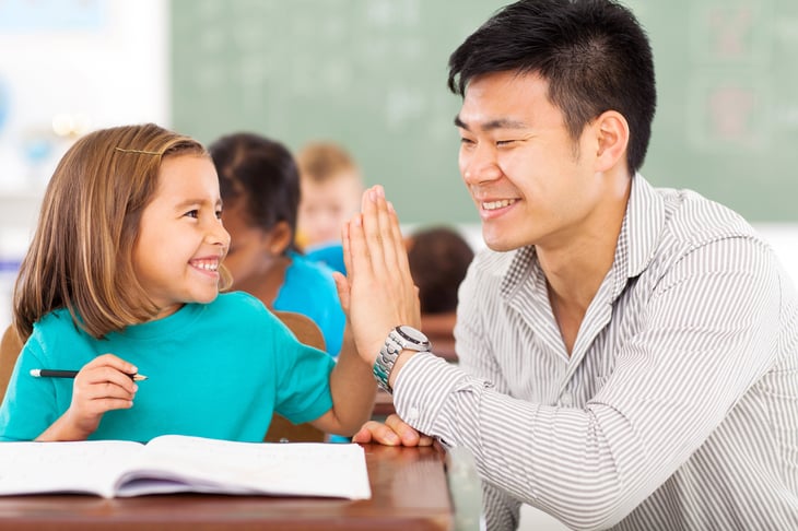 Teacher and student high five in a classroom