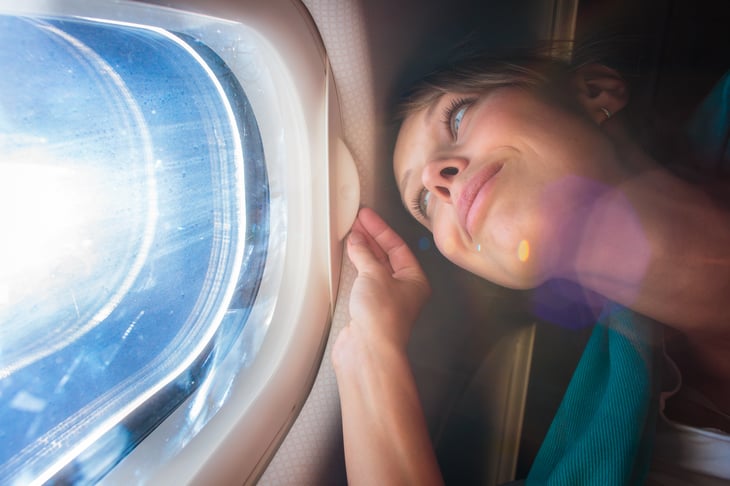 A woman enjoys the view from an airplane cabin window