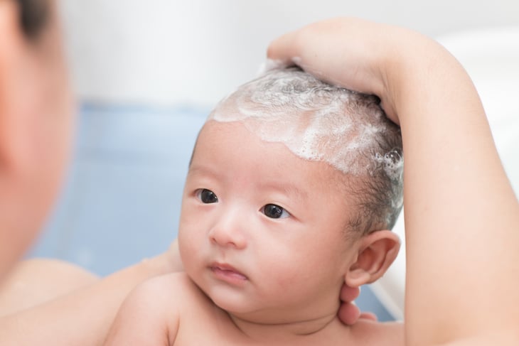 Baby with shampoo lather on his head.