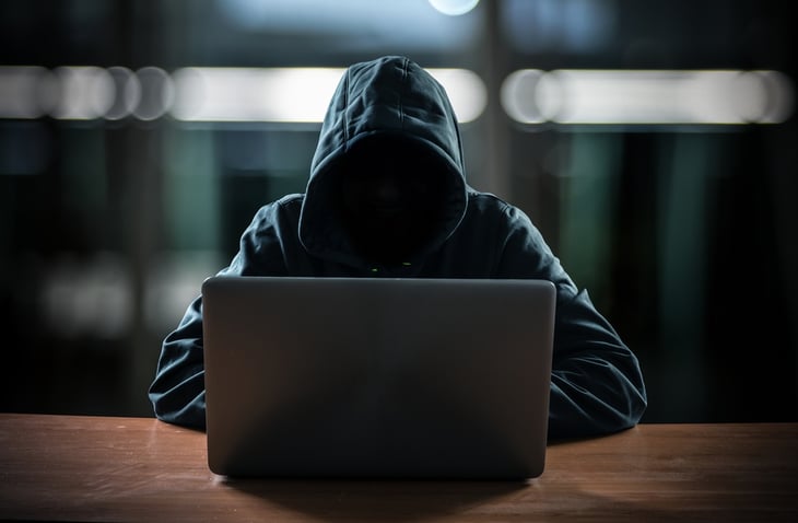 Hooded person working on computer.