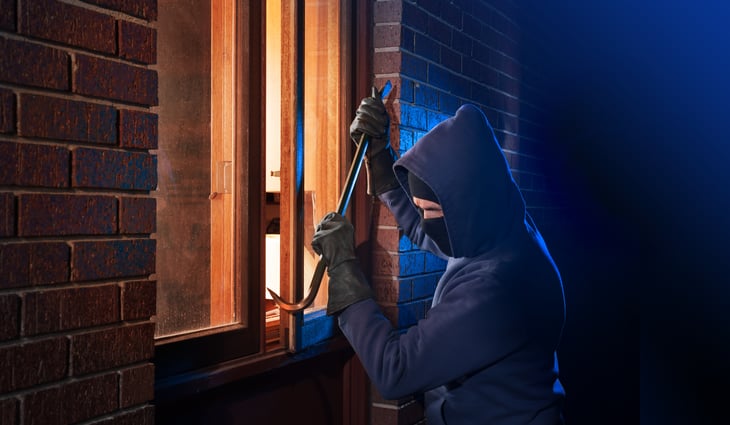 Burglar using crowbar to pry open window