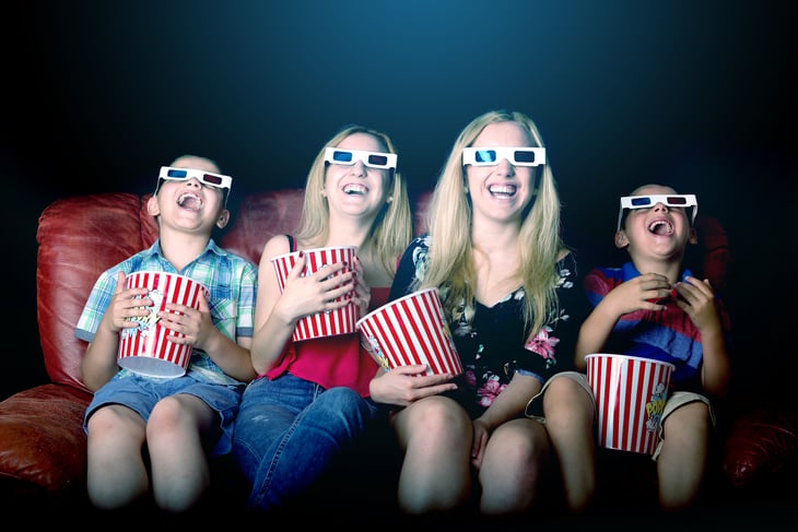 Mom and three kids wearing 3-D glasses, eating popcorn