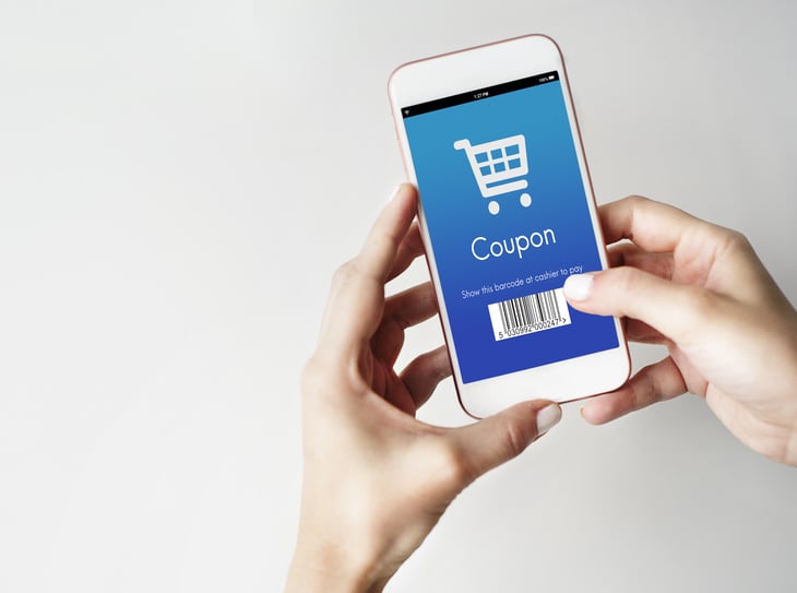 Hands holding a phone with "coupon" on the screen.