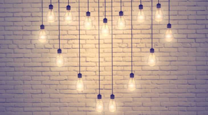 Lightbulb pendants forming a heart against a brick wall.
