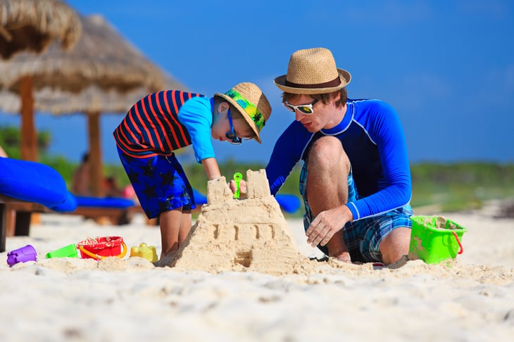 Father and son building sand castle on beach.