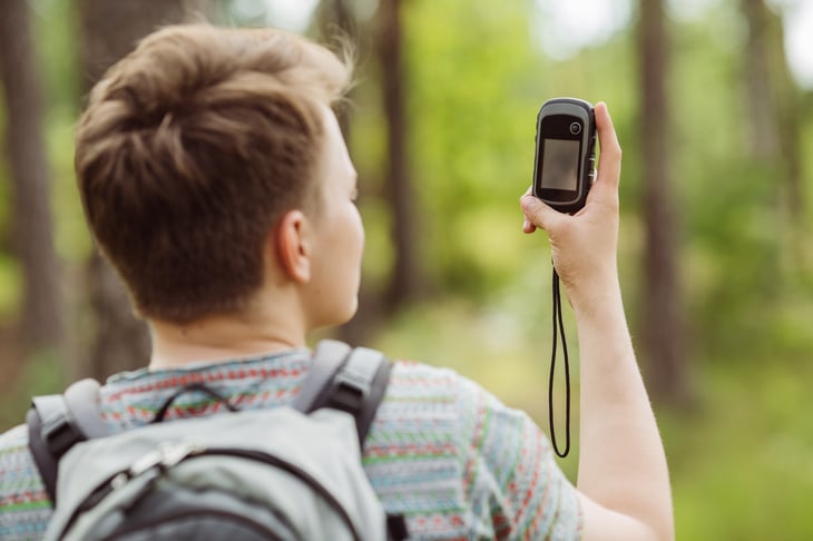 Teen looking at GPS in woods