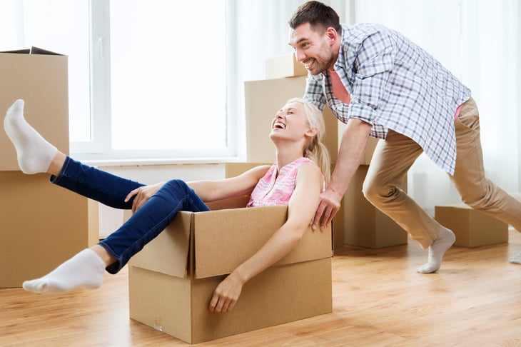 Couple clowning around with moving boxes.