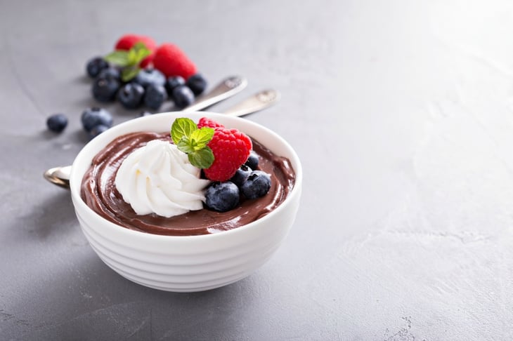 Bowl of chocolate pudding with fruit and whipped cream.