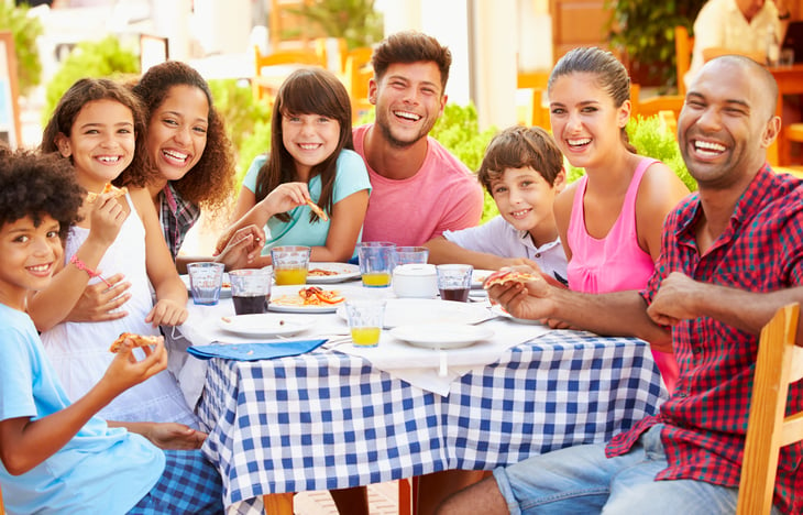 Families sit at table outside eating