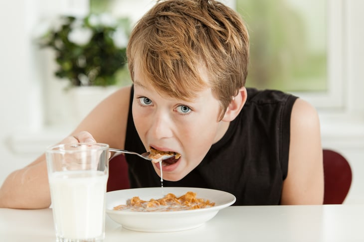 Teenage boy eating cereal.