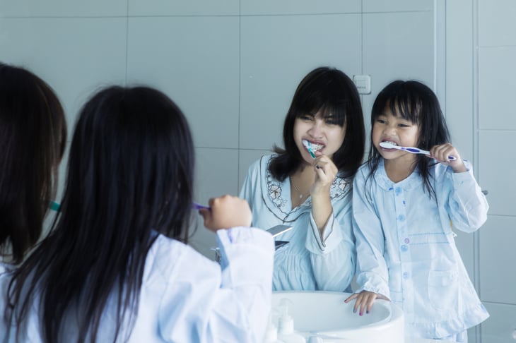 Mom and daughter brushing teeth together,