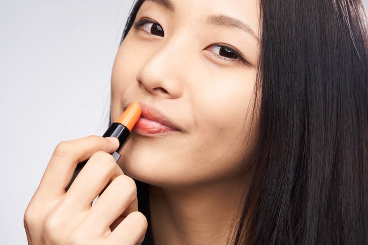 Asian woman applying lipstick