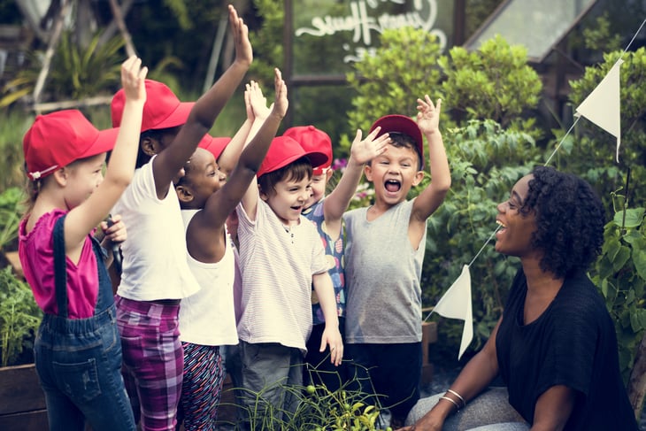 African American woman with grade school students wearing red caps.