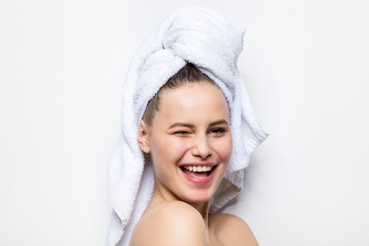 A woman with her hair in a bath towel winks and smiles