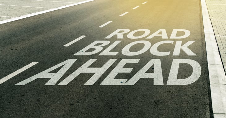 Roadblock ahead written on road.