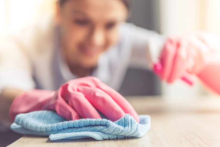 Woman cleaning counter, in soft focus.
