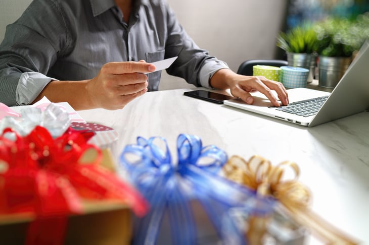 Person working on laptop, card in hand.