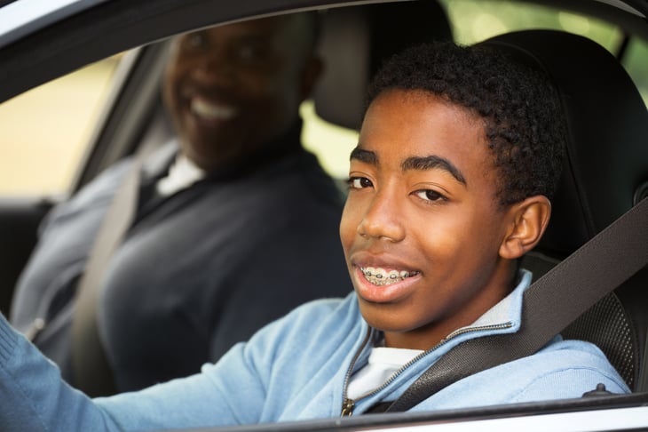 African American teen driving with his father.
