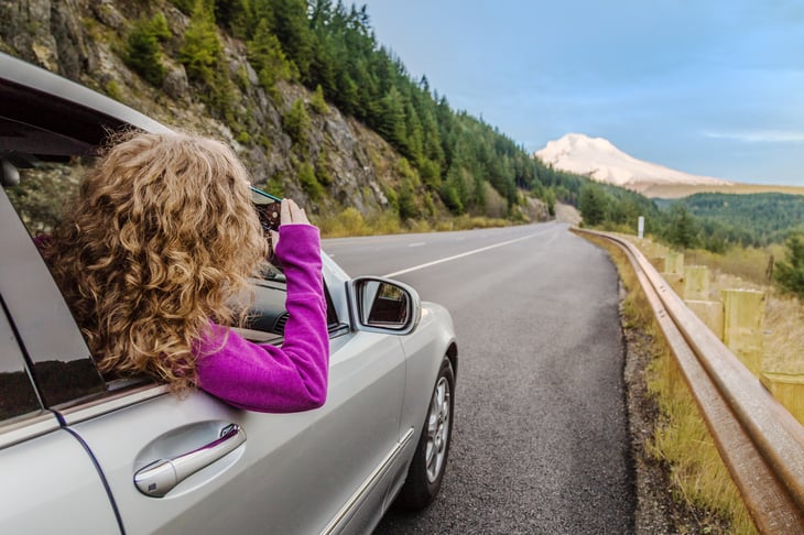 Girl taking a picture from a car window.