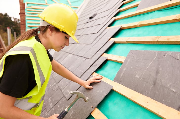Woman working on a roof in construction
