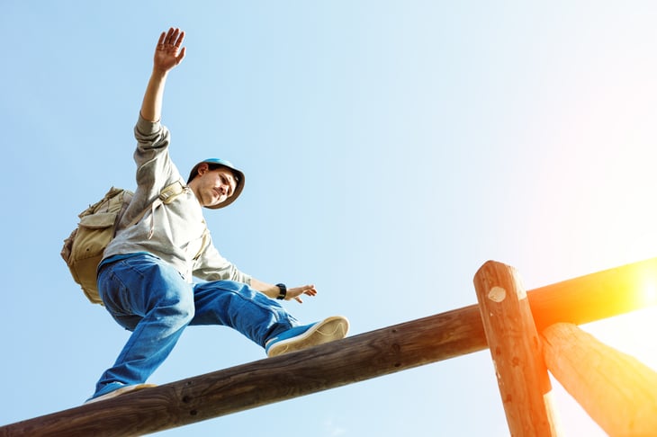 Young man balancing on a fence.