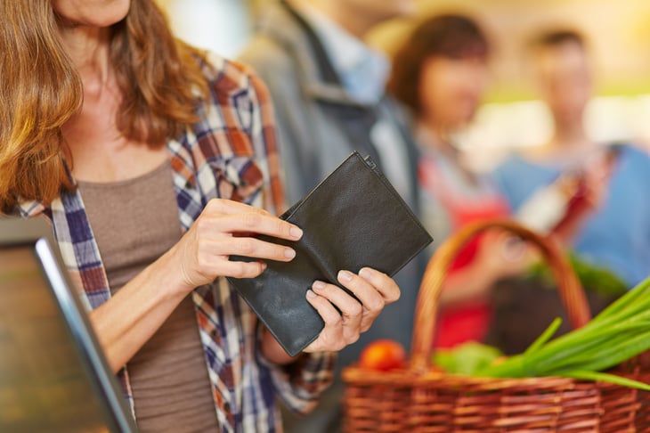 Woman reaching into wallet at checkout stand.