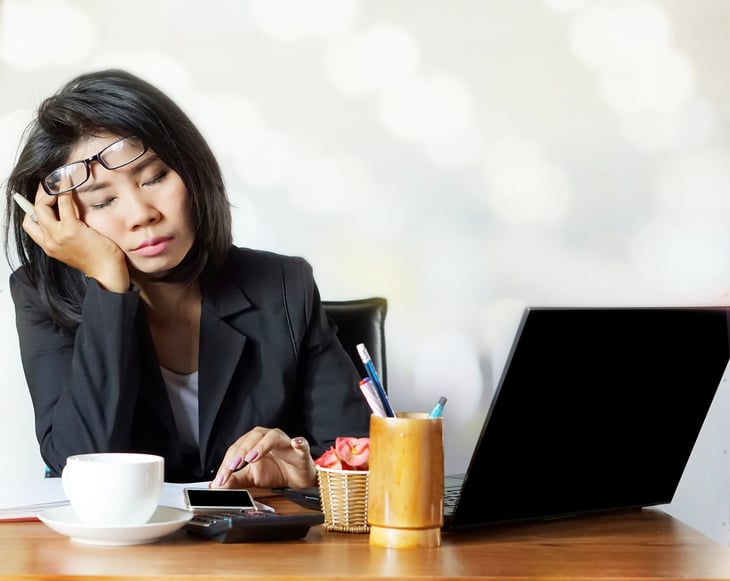 Woman falling asleep at desk.