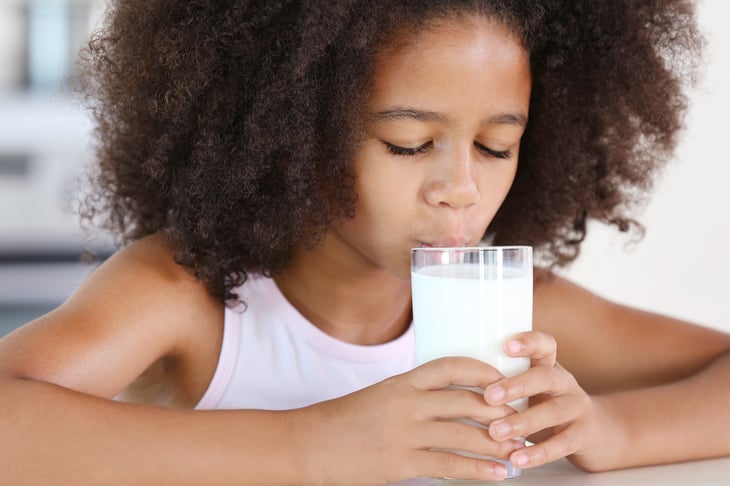 A young girl drinks milk