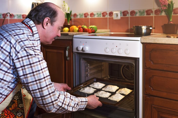 Man removing pies from oven.
